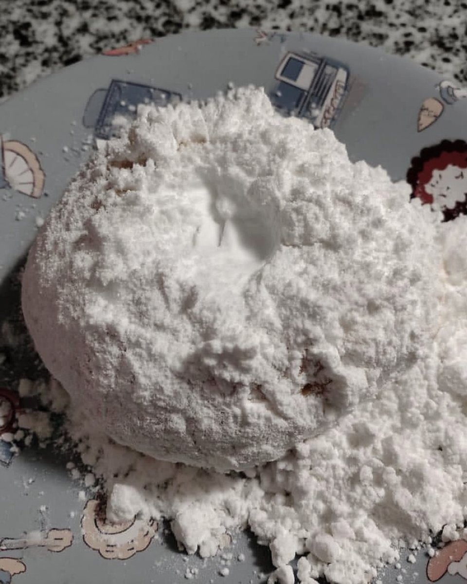 Dredging baked almond cookies in powdered sugar