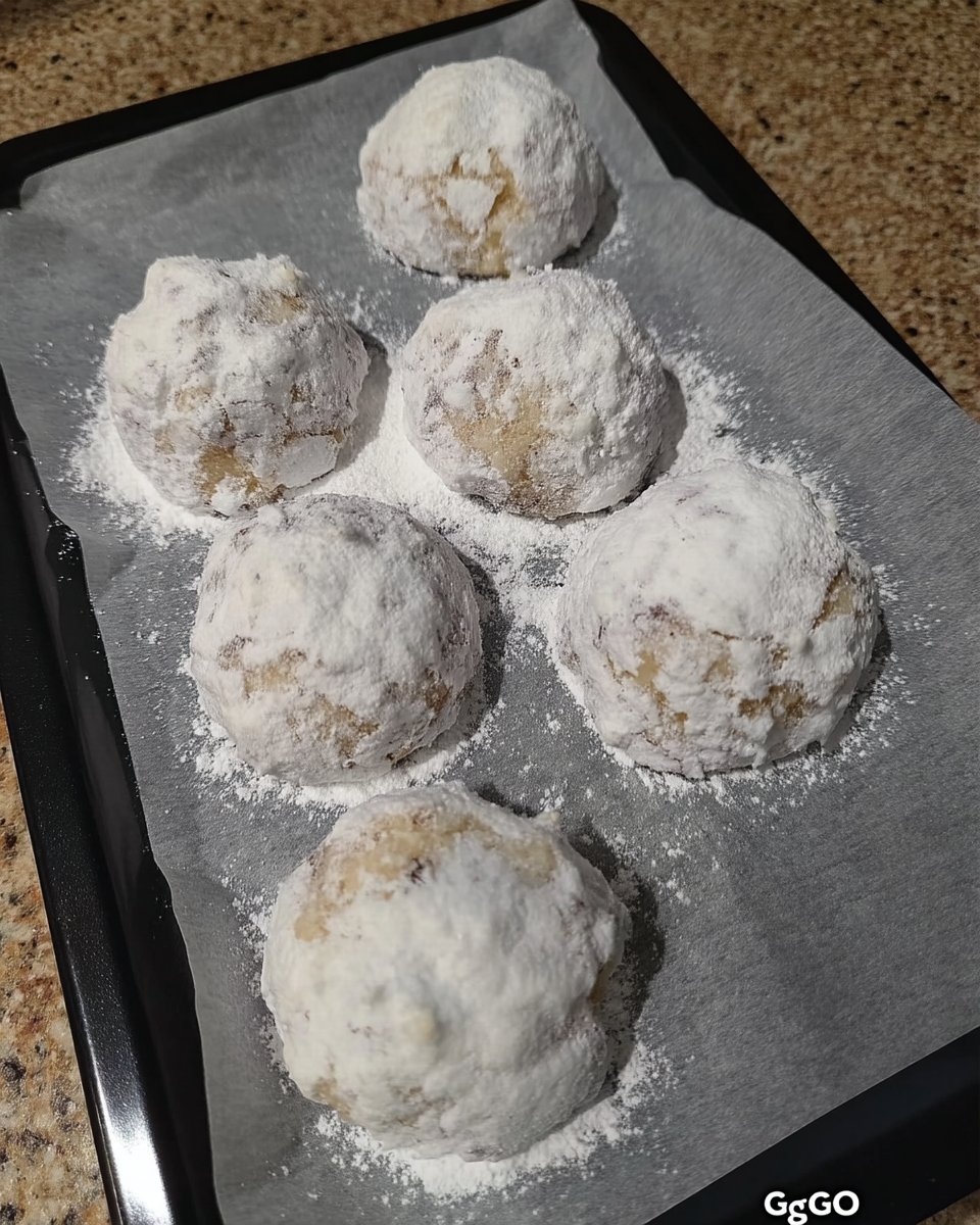 Cookie dough balls being rolled in powdered sugar