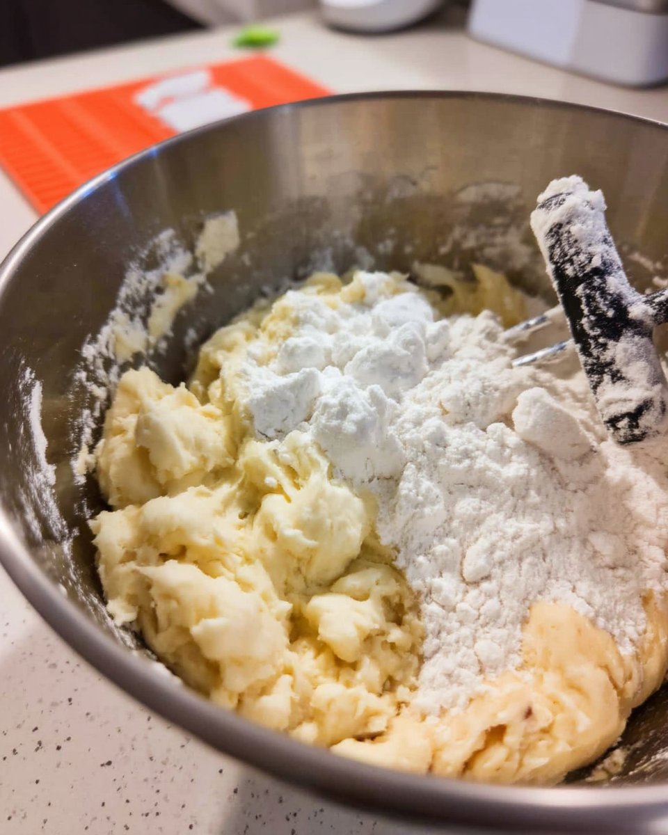 Cookie dough balls being scooped onto a baking sheet with extra chips