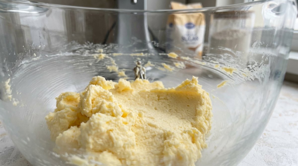 Bowls of flour, sugar, butter, and holiday extracts arranged on a counter