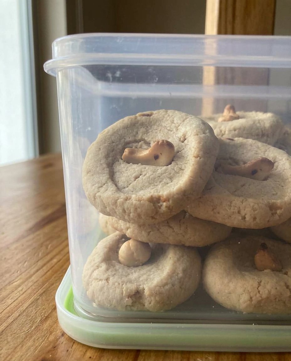 A stack of golden cashew shortbread cookies topped with creamy frosting and whole cashew halves.
