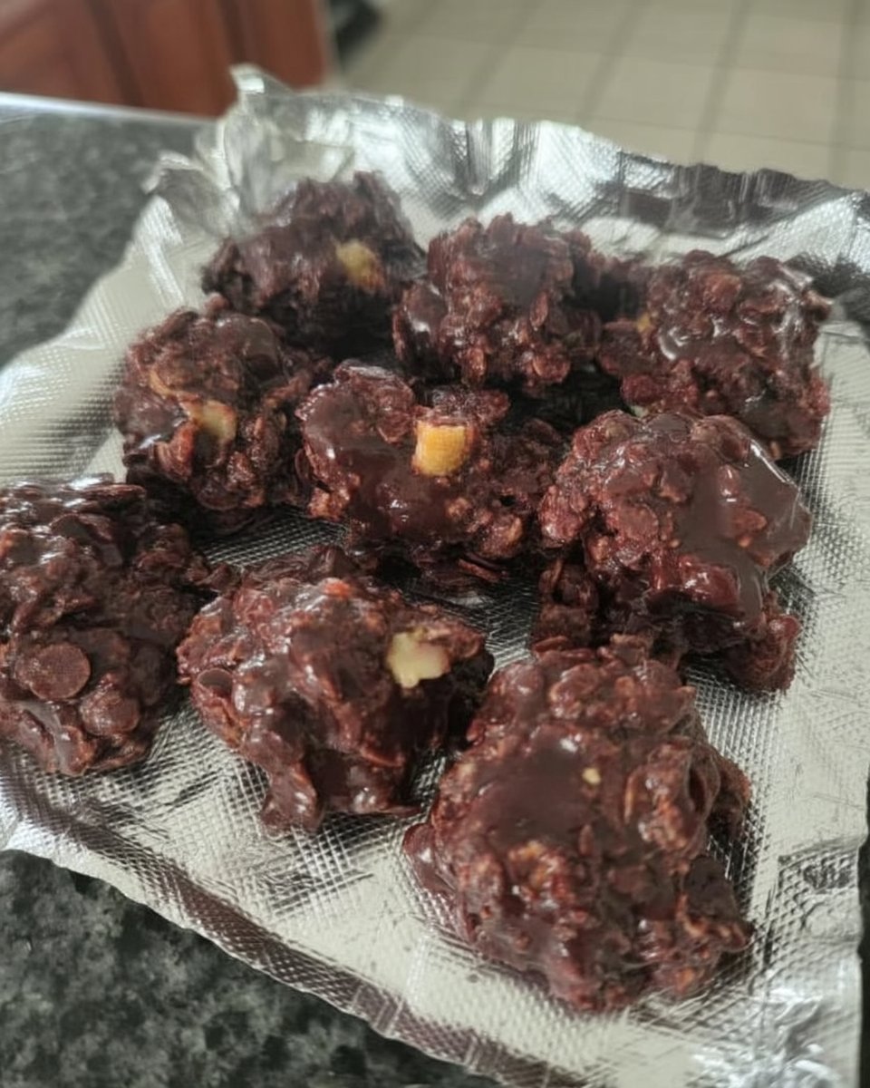 A stack of no bake chocolate oatmeal cookies on a rustic wooden board with a glass of milk