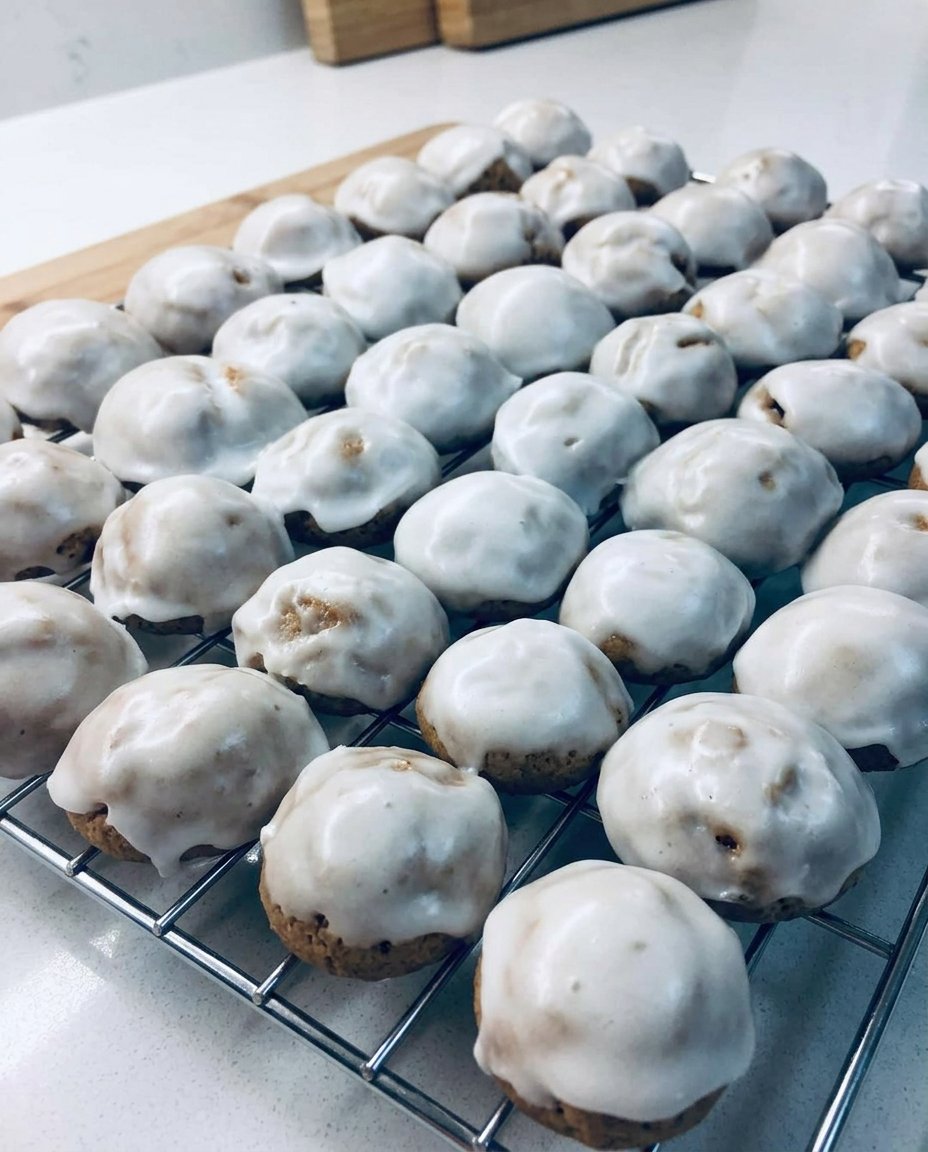 A rustic wooden platter filled with glazed pfeffernusse cookies