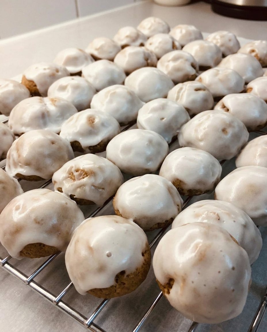 Glazed pfeffernusse cookies on a cooling rack showing natural crackle glaze