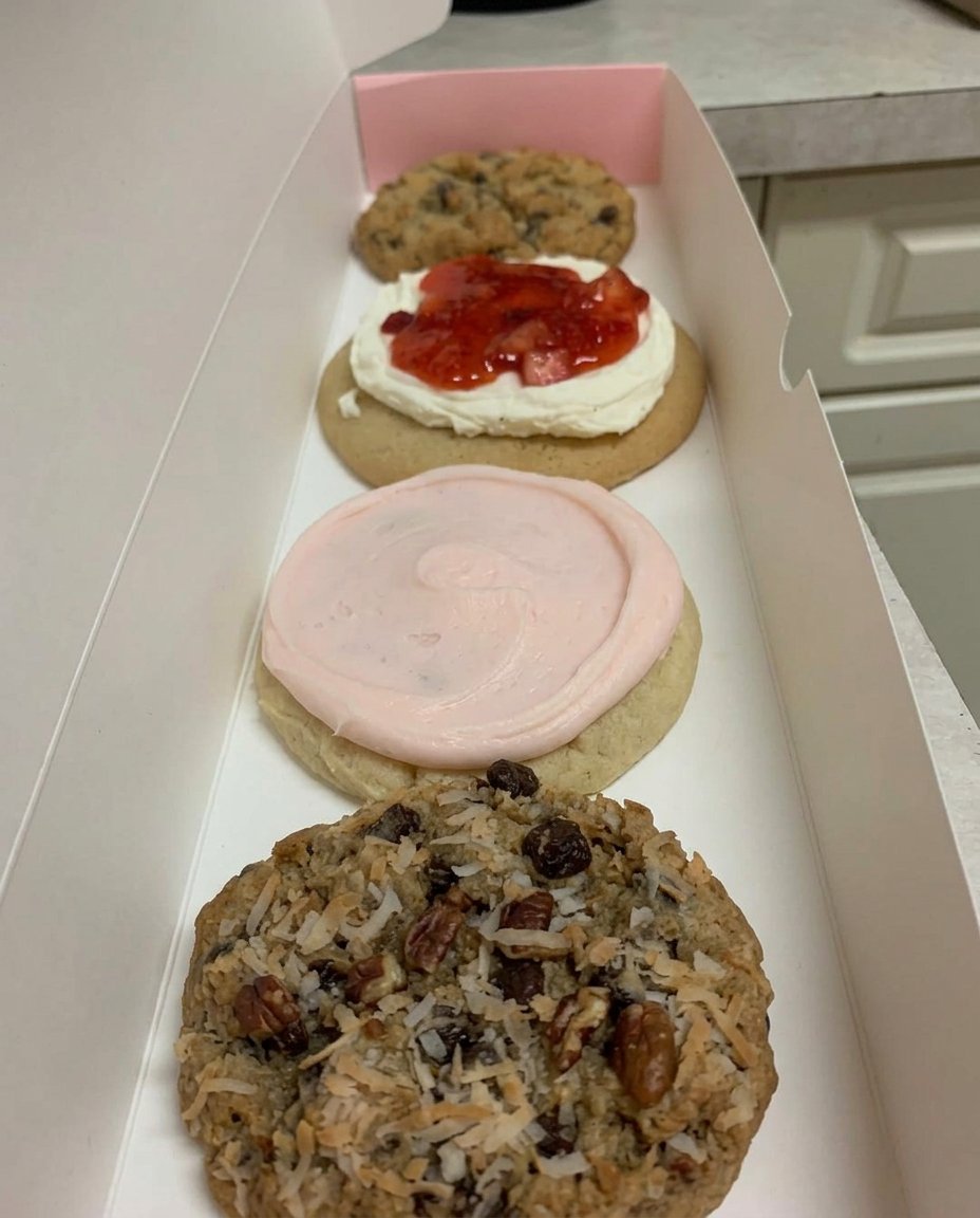 A single warm Crumbl chocolate chip cookie on a plate being broken in half to show the gooey center.