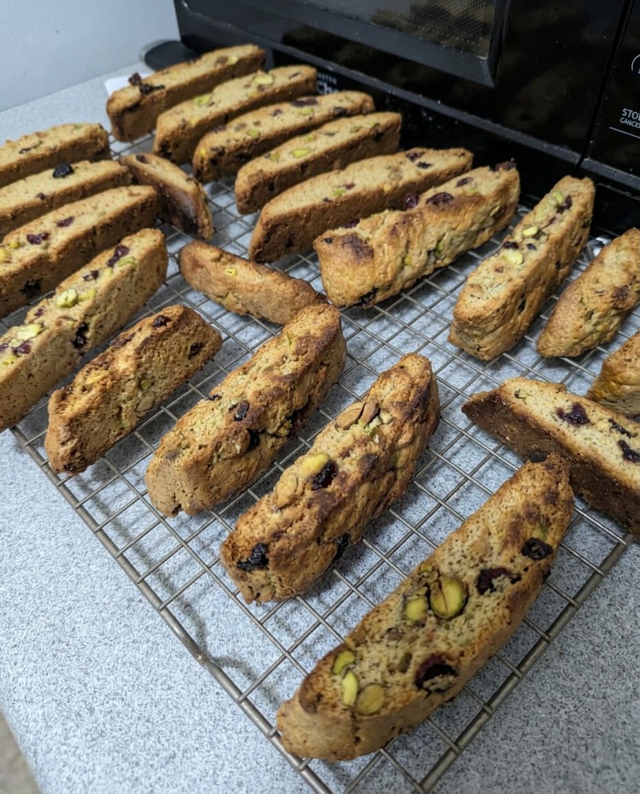 Cranberry pistachio biscotti served on a plate next to a cup of coffee