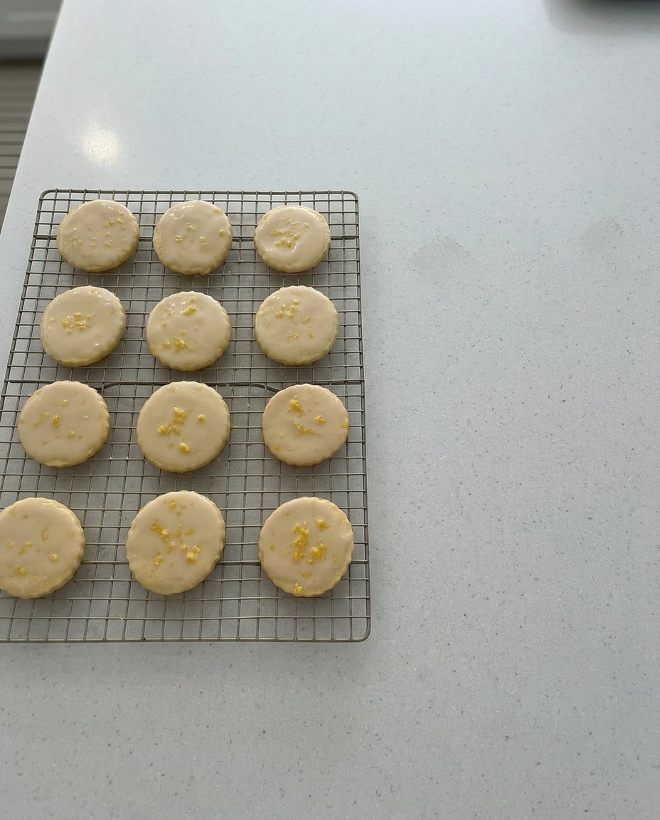 A tray of fresh lemon glazed cookies on a rustic wooden farmhouse table